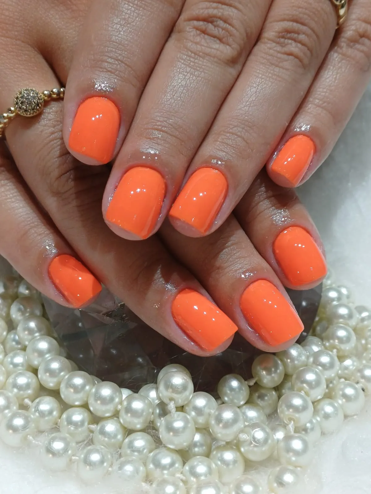 Unhas em gel laranja com decoração de pérolas feitas no Studio Harrod's